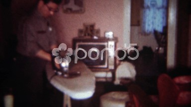1963: Dad irons clothes in living room while daughter sits inches from TV.