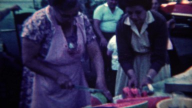 1961: Grandma slicing watermelon for summer picnic festival event. CINCINNATI,