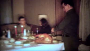 1964: Father carving turkey for intimate holiday candlelight dinner feast.
