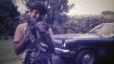 1969: Boy holding 2 lost kitty cats that he found with his camero car. DES