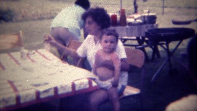 1971: Mother Holding Baby Boy Reading Paper at Family Reunion Picnic in Des Moines