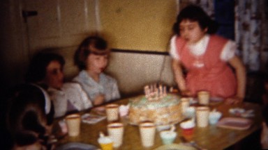 1962: Birthday girl blows out cake candles at home party. BUFFALO, NEW YORK