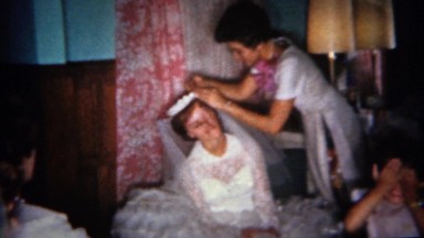 1965: Mother preparing bride for wedding pinning tiara. BUFFALO, NEW YORK