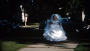 1965: Bride tests out giant white flowing dress in city park. BUFFALO, NEW YORK