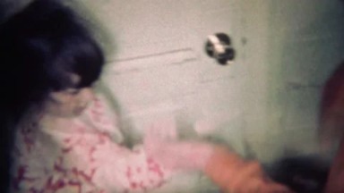 1970: Brother teaches sister how a metal slinky toy works. BOULDER, COLORADO