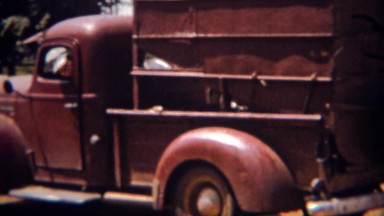 1951: Red farm truck unloads corn grain into storage silos. LINCOLN, NEBRASKA