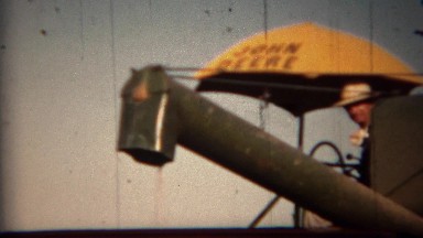 1951: John Deere harvester loading grain into transportation trucks. LINCOLN,