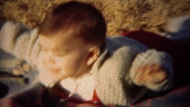 1951: Boy practicing tummy time in sunshine on warm blanket. LINCOLN, NEBRASKA