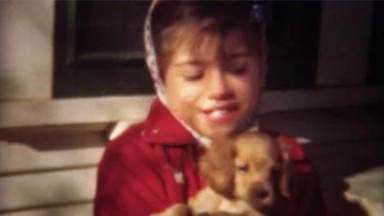 1948: Cute Girl Bundled in Red Coat Plays with Golden Retriever Puppy in Greeley, Colorado