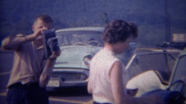 1966: Photographer loads camera while pretty retro women smiles. OAK RIDGE,