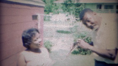 1967:African American man plays flute for wife outdoors. CARMEL, INDIANA