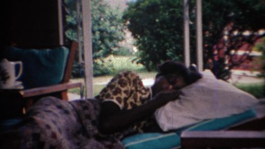 1969: African American girl itching her nose white laying down. CARMEL, INDIANA