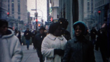 1969: African family waiting on busy urban downtown sidewalk.