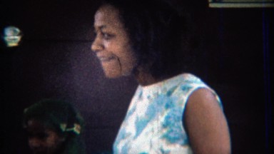 1969: Drunk African women twist dancing in blue floral dress.