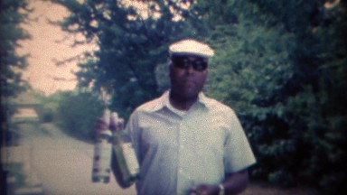 1969: African man clowning rum alcohol liquor bottles.