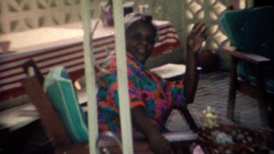 1969: African American Woman in Colorful Shirt and Hair Rollers on Patio