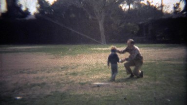 1979: Father teaching son how to fly kite in city park.
