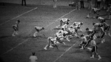 1978: High school football night game quarterback keeps ball.