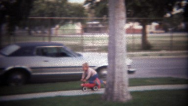 1979: Boy wipes out peddling a cart into grass near cars.