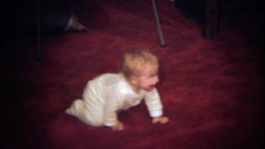 1979: Cute happy baby crawling across carpet floor.