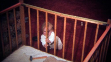 1979: Caucasian baby reaching for dangerous hammer in crib.