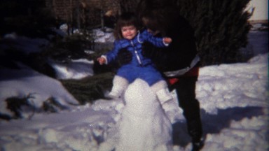 1974: Young Girl in Blue Coat Builds Snowman with Mother in Winter