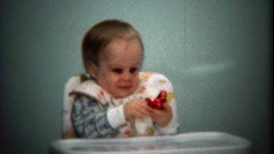 1974: Baby opening red chocolate Valentines Day heart gift.