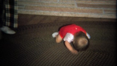 1974: Baby boy crawling head first on carpet rug.