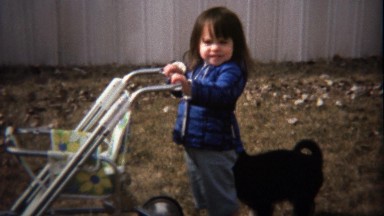 1974: Black puppy tugging little girl asking to play.