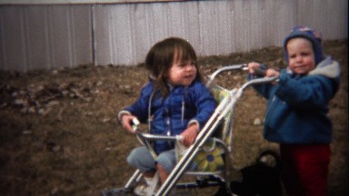 1974: Little brother wants to push sister around backyard in stroller.