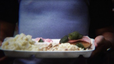 1973: Boy licking his lips anticipating eating plate of outdoor picnic food.