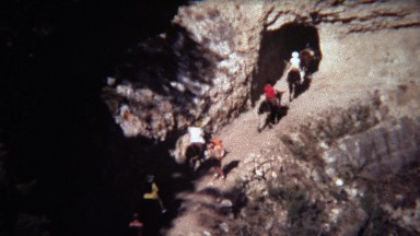 1972: Horse riding group going into rocky dry dark unknown tunnel.