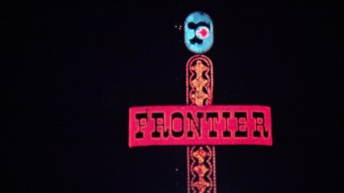 1972: Frontier hotel casino neon sign at night downtown bright lights.