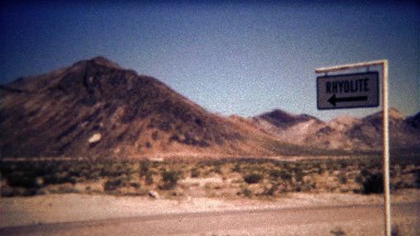 1972: Ghost Town mining camp sign and abandoned brick building ruins.