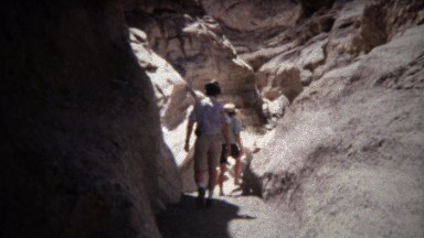 1971: Hikes walking on dry trail rocky smooth cavern cliffs.