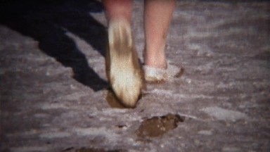1971: Shoes walking through thick mud on dry lake bed.