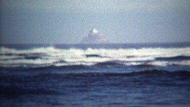 1971: Magic island floating above ocean in near fata morgana mirage.