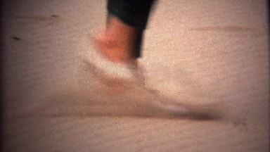 1971: Women shoes closeup walking in deep yellow sand dirt.