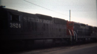 Southern Pacific Train Hauling Lumber Next to Car Driving Road