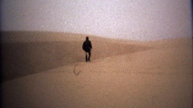 1971: Man walking in blonde yellow sand desert alien landscape.