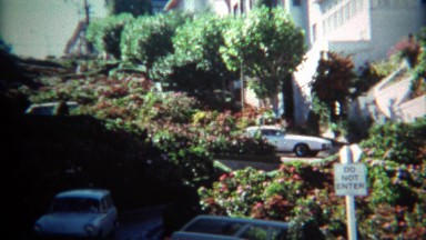 1971: Car turning on curvy famous flower covered Lombard Street.
