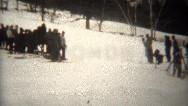 1939: Daredevil downhill skiers taking sharp turn with audience.