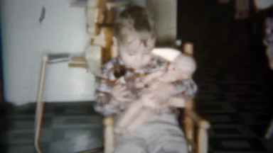 1962: Toddler boy feeding and kissing plastic baby doll.