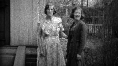 1933: Mother daughter in formal dress play wrestling in front yard.