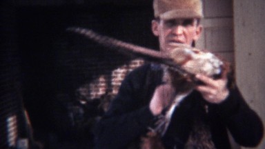 1939: Hunting man wears dead pheasant birds necklace.