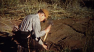 1940: Man Setting Up Hunting Blind and Camping Tent with Axe Hammer