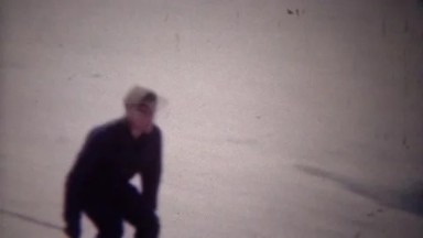 1949: Man downhill snow skiing to winter resort hotel lodge.