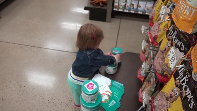 Toddler unstacking plastic jars at pet store practicing spatial learning.