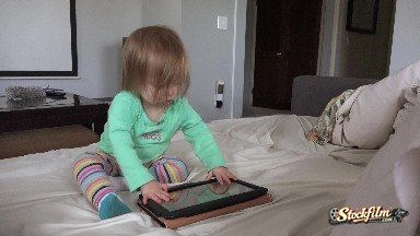 Denver, Colorado, United States: Toddler Tablet Computing in Living Room Seated on White Day Bed.