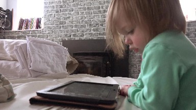 Toddler playing with tablet computer closeup touching screen.